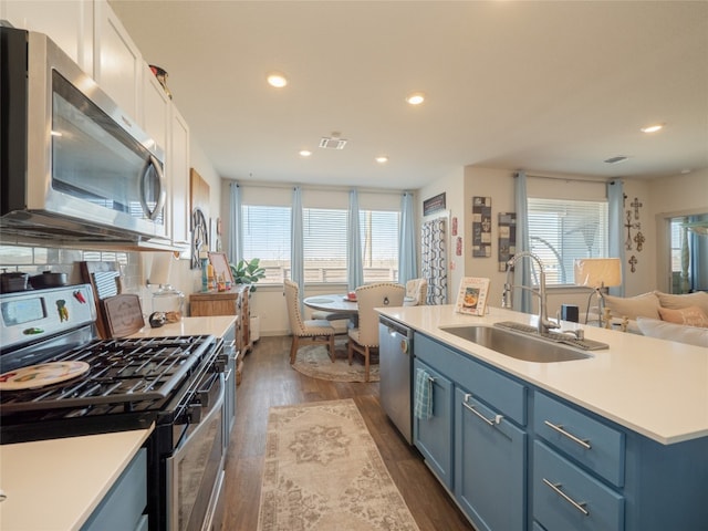 kitchen featuring appliances with stainless steel finishes, sink, white cabinets, a center island, and blue cabinetry