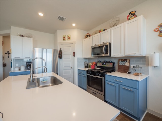 kitchen featuring appliances with stainless steel finishes, white cabinetry, sink, decorative backsplash, and a center island with sink