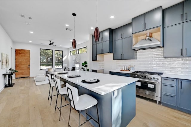 kitchen with stainless steel gas stove, a kitchen breakfast bar, light hardwood / wood-style floors, a kitchen island, and decorative light fixtures