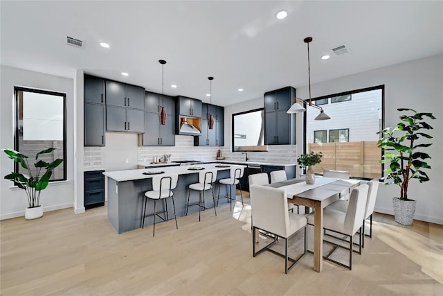 kitchen with hanging light fixtures, a center island, light hardwood / wood-style floors, and decorative backsplash