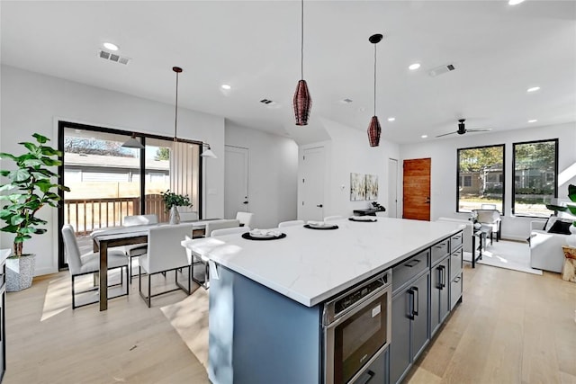 2717 Lyons Rd Unit 1, Austin, TX 78702 - kitchen featuring stainless steel microwave, light wood-style floors, a kitchen island, open floor plan, and recessed lighting