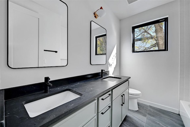 bathroom featuring vanity, a washtub, and toilet