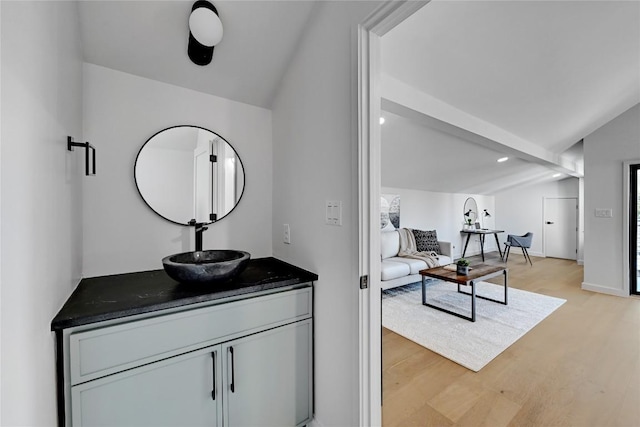 bathroom featuring hardwood / wood-style flooring, vaulted ceiling, and vanity