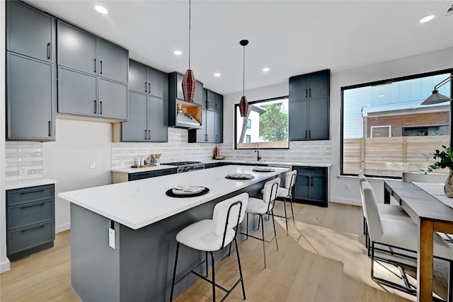 kitchen with gray cabinets, pendant lighting, sink, a center island, and light hardwood / wood-style floors