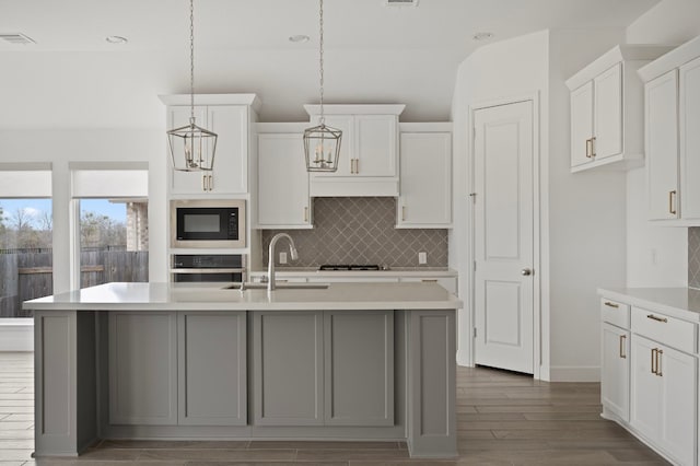 kitchen featuring built in microwave, stainless steel oven, and a center island with sink