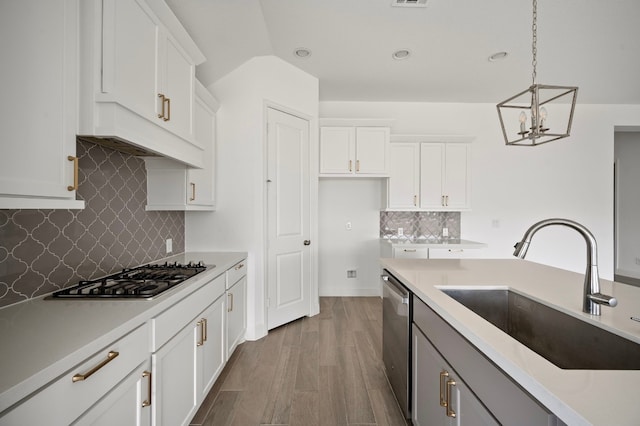 kitchen with appliances with stainless steel finishes, hardwood / wood-style floors, decorative light fixtures, sink, and white cabinets