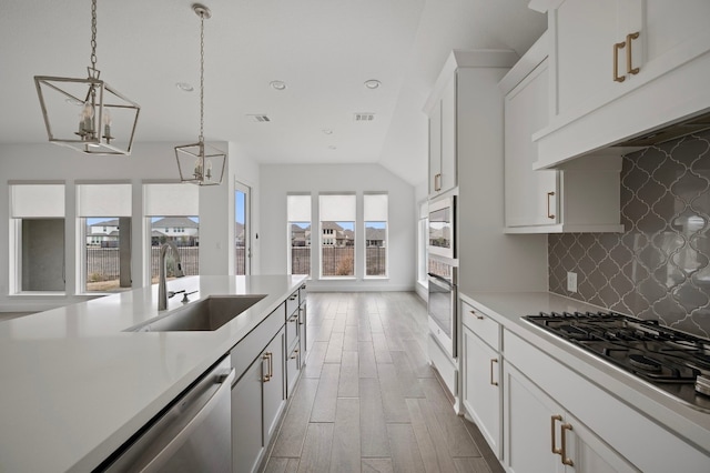 kitchen featuring white cabinets, sink, gas cooktop, and decorative light fixtures