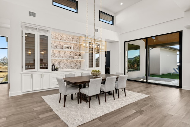 dining room with wood-type flooring, a towering ceiling, and a chandelier