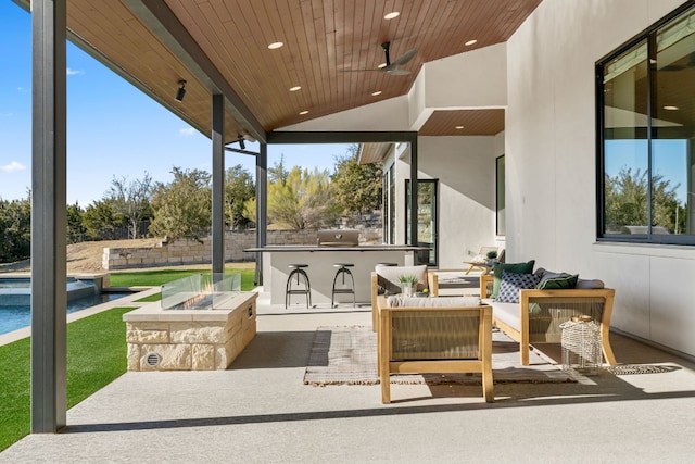 view of patio featuring exterior kitchen, an outdoor living space with a fire pit, and ceiling fan