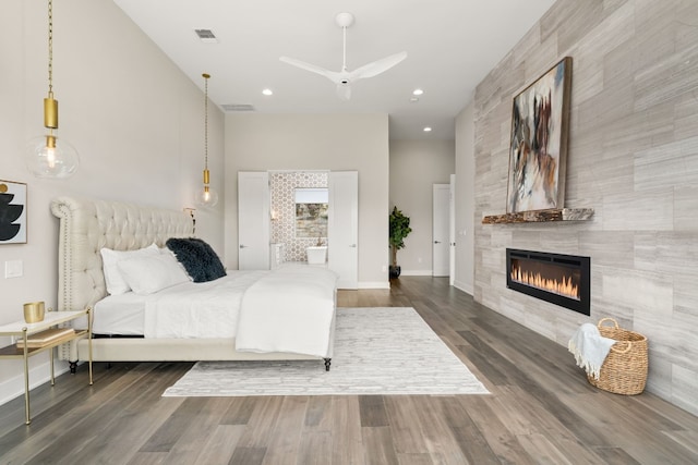 bedroom featuring ceiling fan, dark hardwood / wood-style flooring, and a tile fireplace