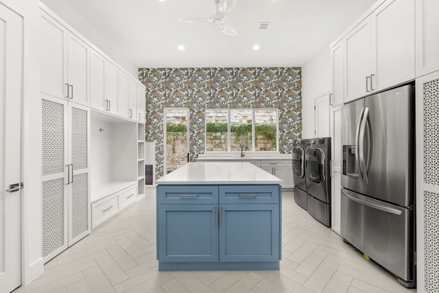 kitchen with blue cabinets, white cabinetry, washer and dryer, and stainless steel fridge