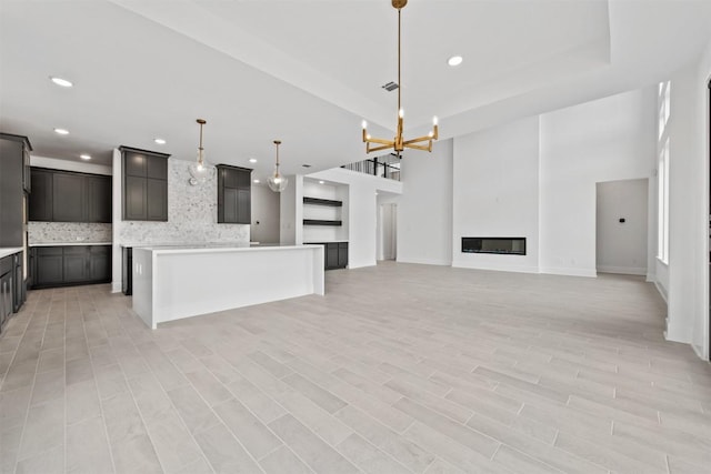 unfurnished living room with a towering ceiling and an inviting chandelier