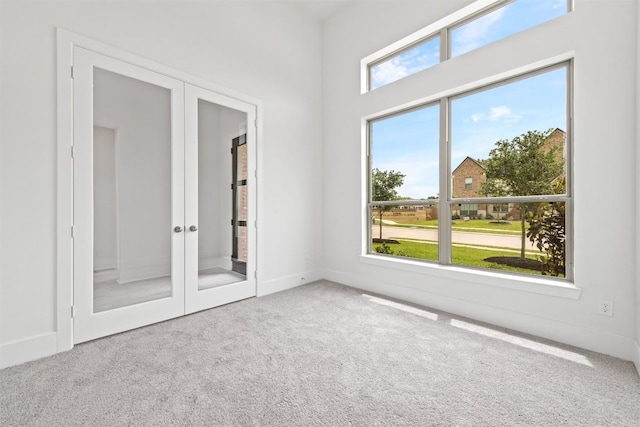 carpeted spare room featuring french doors and a wealth of natural light