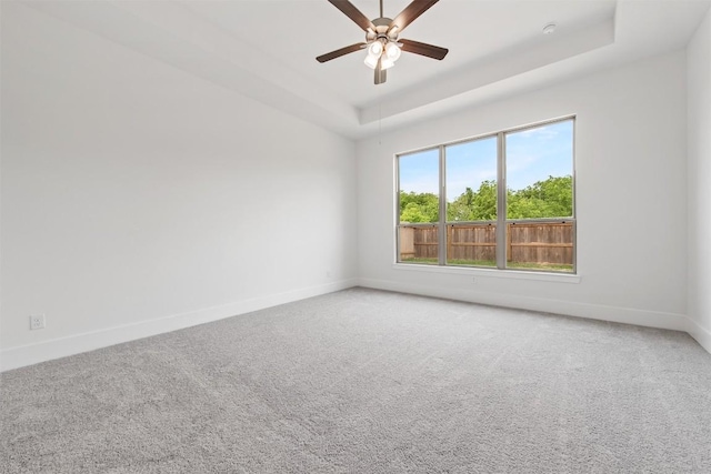 spare room with carpet flooring, ceiling fan, and a tray ceiling