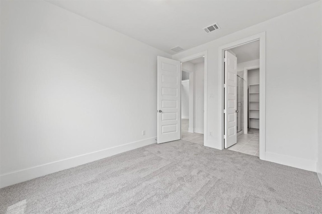 unfurnished bedroom with light colored carpet and a closet