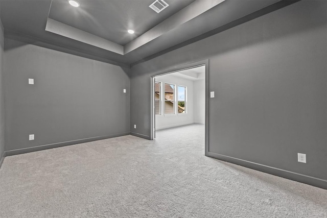 carpeted spare room featuring a raised ceiling