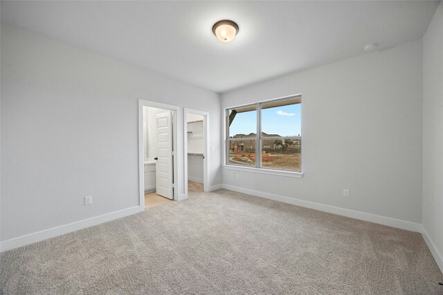unfurnished bedroom with a spacious closet, baseboards, and light colored carpet