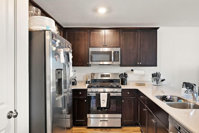 13413 Mussel Run, Elgin, TX 78621 - kitchen with appliances with stainless steel finishes, dark brown cabinetry, light wood-style flooring, light countertops, and a textured ceiling