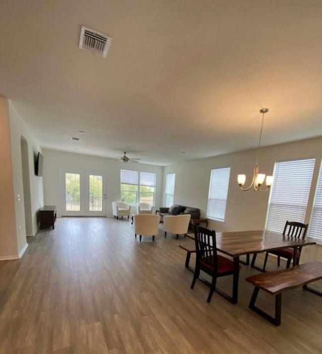 dining space featuring wood-type flooring and ceiling fan with notable chandelier