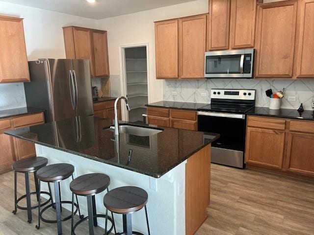 kitchen with an island with sink, appliances with stainless steel finishes, sink, and a kitchen breakfast bar