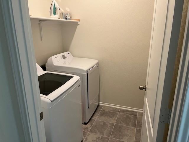 laundry room with washer and dryer and dark tile patterned floors