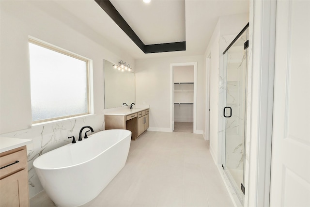 bathroom featuring a walk in closet, a soaking tub, vanity, and a marble finish shower