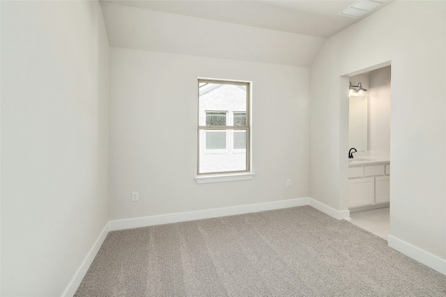 unfurnished room featuring baseboards, visible vents, light colored carpet, lofted ceiling, and a sink