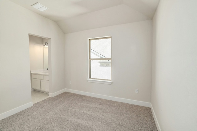 spare room with light colored carpet, visible vents, a sink, vaulted ceiling, and baseboards