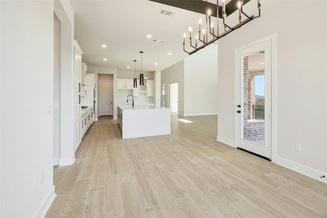 kitchen featuring a sink, visible vents, white cabinets, light countertops, and light wood-type flooring