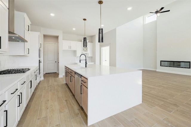 kitchen featuring dishwasher, a glass covered fireplace, light wood-type flooring, gas cooktop, and a sink