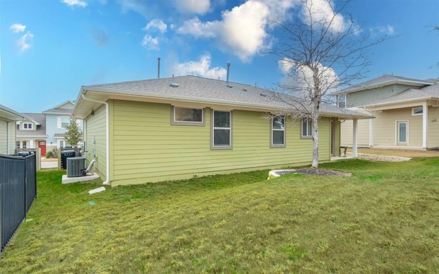 back of property with central AC unit and a lawn