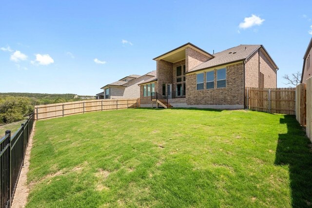 7420 Desert Needle Dr, Lago Vista, TX 78645 - back of house with brick siding, a fenced backyard, and a lawn