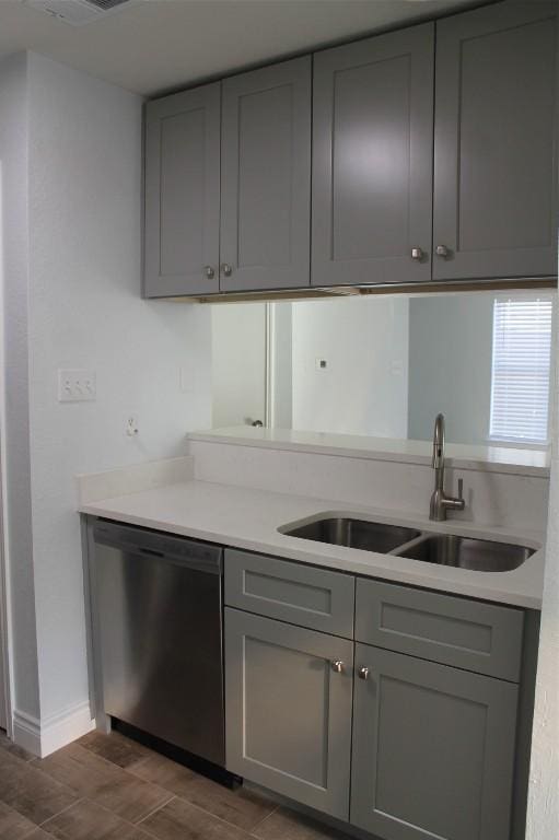 kitchen featuring dishwasher, sink, and gray cabinetry