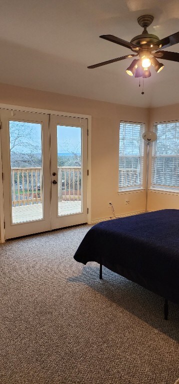 carpeted bedroom with ceiling fan, access to exterior, and multiple windows