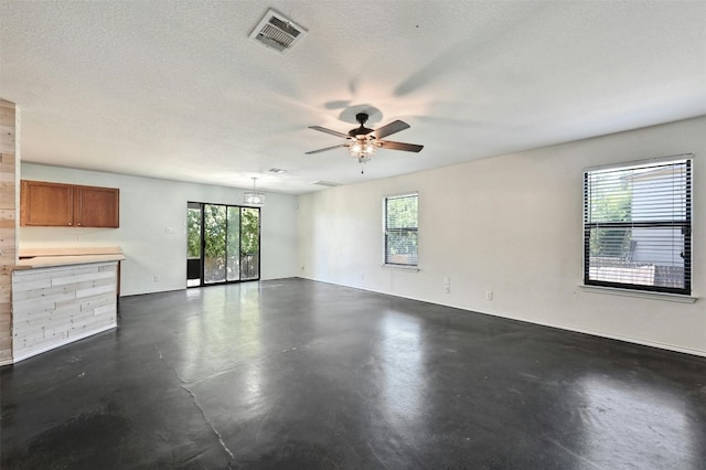 unfurnished room with ceiling fan and a textured ceiling