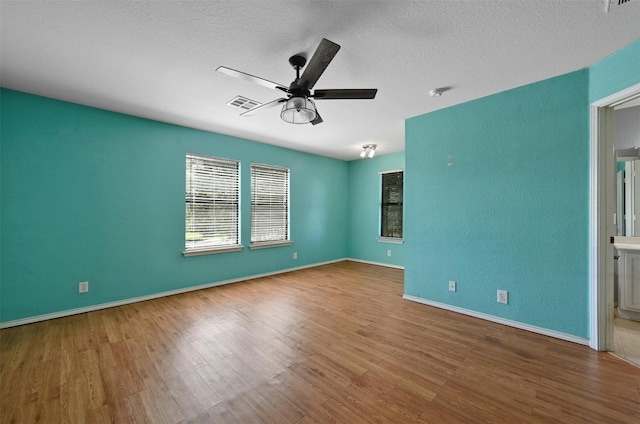 empty room featuring ceiling fan, hardwood / wood-style floors, and a textured ceiling