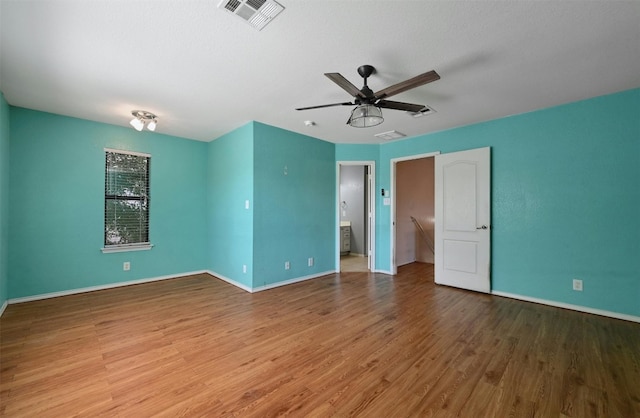 unfurnished bedroom featuring hardwood / wood-style flooring, a textured ceiling, ceiling fan, and ensuite bath