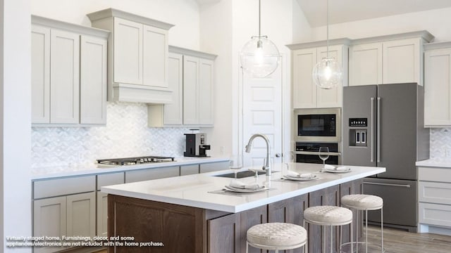 228 La Venta Loop, Liberty Hill, TX 78642 - kitchen with stainless steel appliances, a sink, backsplash, light countertops, and a center island with sink