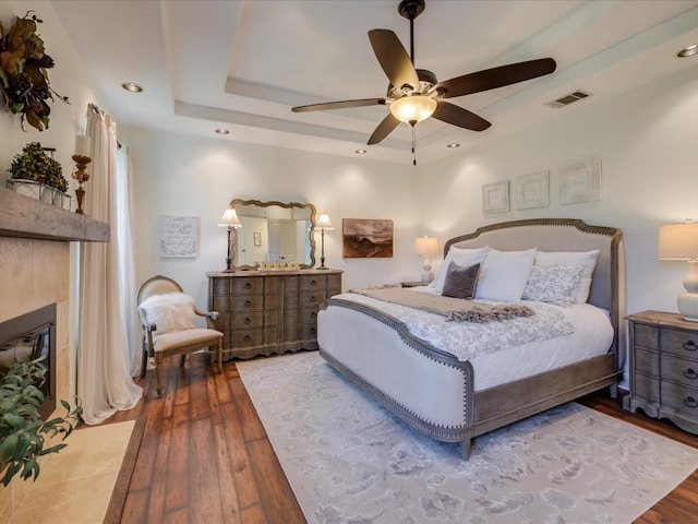 bedroom featuring dark hardwood / wood-style flooring, ceiling fan, and a tray ceiling