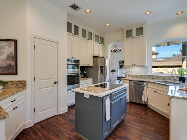 kitchen featuring sink, appliances with stainless steel finishes, dark hardwood / wood-style floors, a center island, and white cabinets