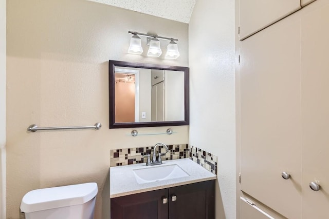 bathroom with vanity, toilet, and decorative backsplash