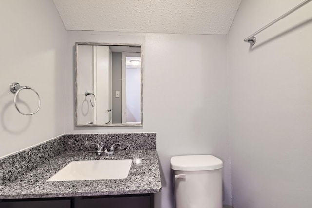 bathroom with vanity, a textured ceiling, and toilet