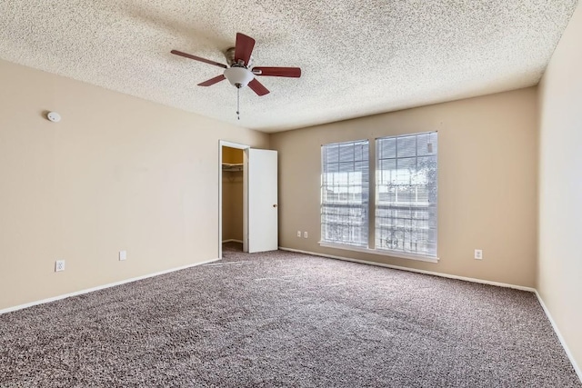 unfurnished bedroom with a spacious closet, a textured ceiling, carpet floors, a closet, and ceiling fan