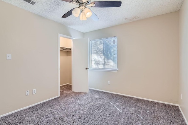 unfurnished bedroom featuring ceiling fan, carpet floors, a textured ceiling, a walk in closet, and a closet