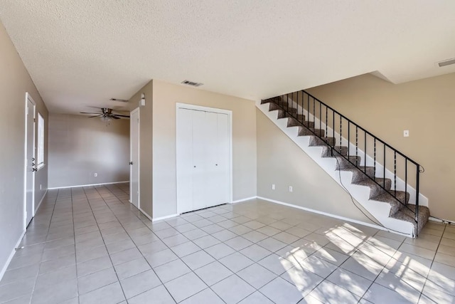 unfurnished room with light tile patterned flooring, ceiling fan, and a textured ceiling