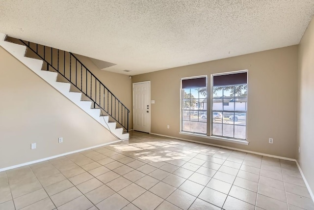 unfurnished room featuring a textured ceiling and light tile patterned floors