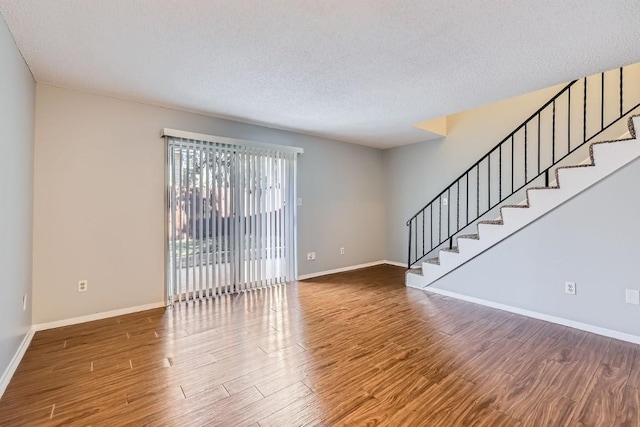 unfurnished room with wood-type flooring and a textured ceiling