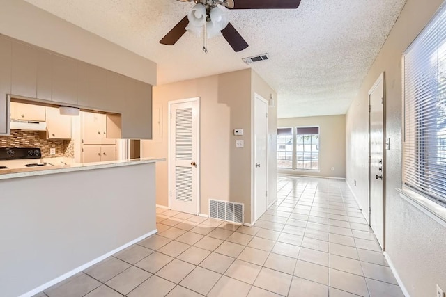 kitchen with tasteful backsplash, a textured ceiling, stove, and light tile patterned flooring