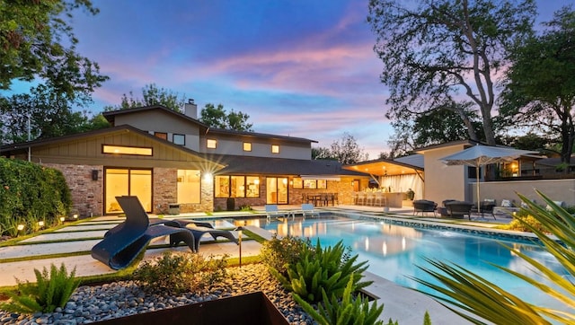 pool at dusk featuring a patio