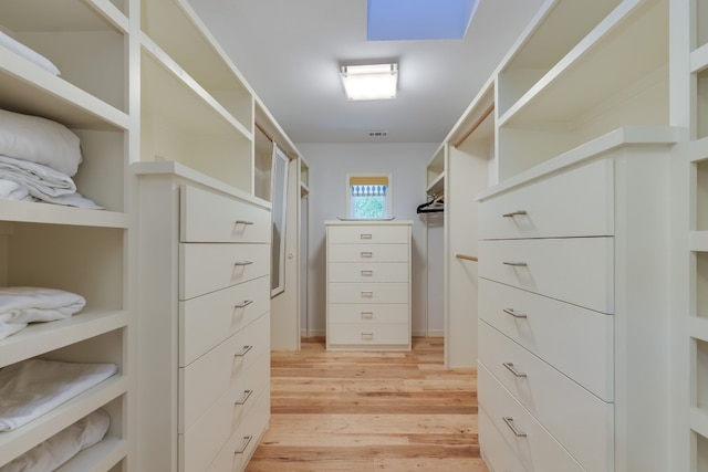 walk in closet with a skylight and light wood-type flooring